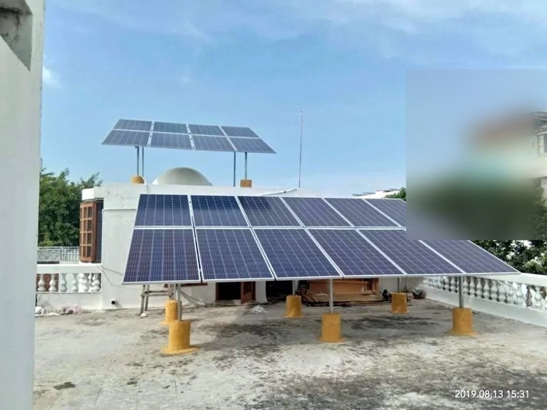 Solar panels installed on rooftop with additional tracking panels mounted on roof structure and yellow bollards below